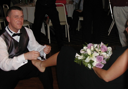 Eric puts the garter on his date's leg.