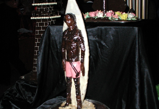 Chocolate surfer with a surf board behind him.